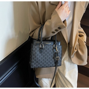 Détail du sac à main noir en cuir avec motif M et boucles métalliques dorées chic