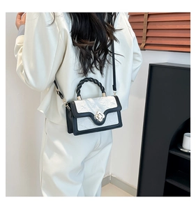Detail of clover metal buckle and woven handle on black and white crossbody bag