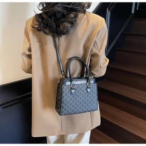 Close-up of stylish letter print tote bag worn by model in a professional blazer