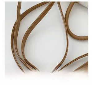 Macro shot of brown leather shoulder strap and handle with premium stitching detail