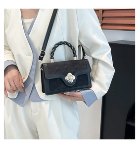 Close-up of black crossbody bag with twisted handle and silver clover metal buckle