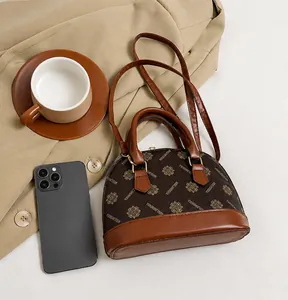 Detailansicht einer braunen Muschel-Tasche mit Blumenmuster und Schulterriemen von oben