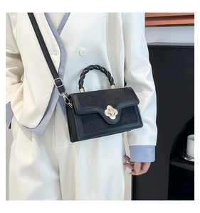 Detail of a black leather handbag featuring a gold floral clasp and woven handle