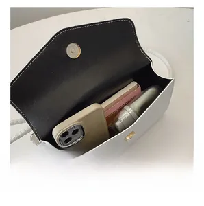 Vue détaillée de l'intérieur du sac blanc montrant l'espace de rangement et le fermoir doré