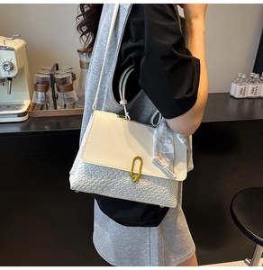 Dettaglio borsa a mano intrecciata con foulard di seta e fibbia dorata al caffè