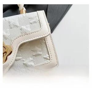 Detail of white handbag with textured fabric and golden floral metal clasp hardware