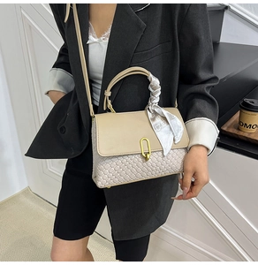 Dettaglio borsa a tracolla con texture intrecciata, chiusura a U dorata e foulard di seta