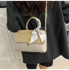 Dettaglio borsa a mano intrecciata con patta in pelle crema e fibbia in metallo oro