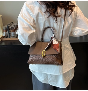 Dettaglio borsa marrone intrecciata con chiusura dorata e foulard decorativo in seta