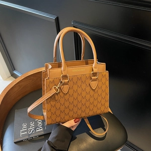 Classic brown monogram tote bag with gold metal logo on a stylish vintage wooden chair