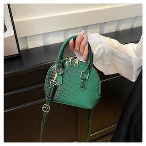 Detail of green crocodile texture shell bag with golden double zippers and handle