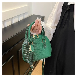 Detail of dark green crocodile texture shell bag with polished gold hardware accents