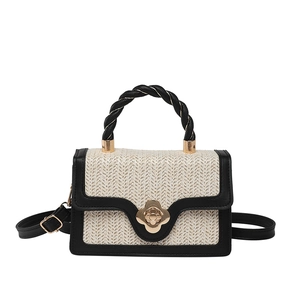 Minimalist woven crossbody bag with black trim and a decorative gold flower buckle