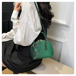 Close-up of green crocodile pattern shell bag with metal zipper and leather strap