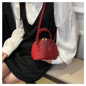 Close-up of red crocodile pattern shell bag with golden zippers and detachable strap