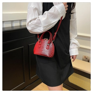 Red crocodile pattern shell bag worn by model with metallic zippers and top handle