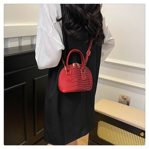 Rear view of a model wearing a red crocodile texture shell bag with adjustable strap