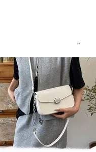 Detail of cream saddle bag featuring lychee grain leather and silver metal buckle closure