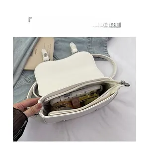 Interior view of white pebble leather saddle bag with compartments for phone and makeup