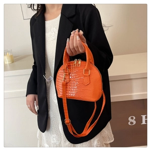Detailed view of orange crocodile texture on shell handbag with gold hardware accents