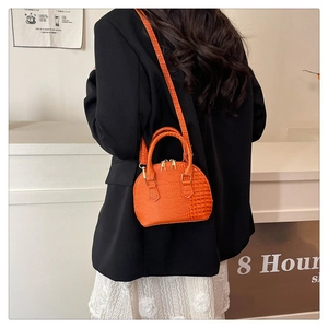 Model wearing a bright orange crocodile pattern shell bag with golden zipper and handle