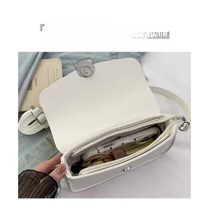 Detail of off-white lychee leather saddle bag showing interior compartments and metal snap