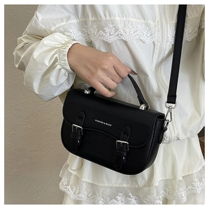 Detail of black vintage saddle bag with silver metal buckles and litchi grain texture