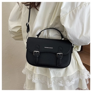 Detail of black lychee grain leather saddle bag with silver double buckles and strap