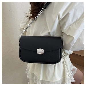 Detail of black lychee grain saddle bag with silver metal lock and chain strap on model