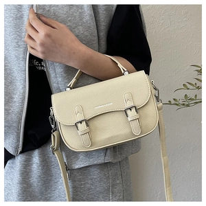 Close-up of beige lychee texture PU leather bag with silver buckle and adjustable strap