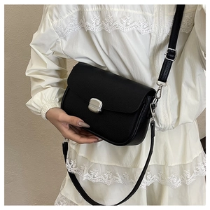 Detail of black lychee grain leather saddle bag with silver buckle worn by a model