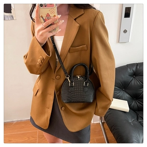 Detail of black faux leather shell bag with crocodile texture on brown blazer outfit