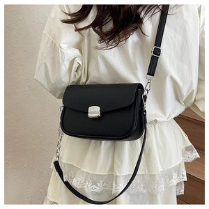 Detail of black pebbled leather saddle bag with silver metallic buckle and chain strap