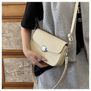 Detail of beige pebble leather saddle bag with silver buckle and detachable strap