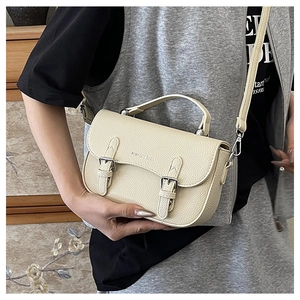 Detail of beige pebble leather handbag showing stitch texture and silver buckle straps