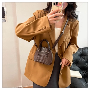 Detailed view of dark brown crocodile-textured mini bag on a mirror selfie model