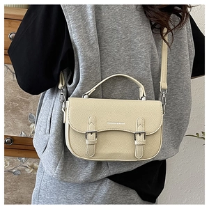 Detail of off-white lychee texture faux leather bag with stylish double buckle flap