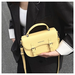 Detail of yellow pebbled leather saddle bag with silver buckles and adjustable strap