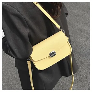 Detail of yellow lychee leather saddle bag with silver buckle worn by a model