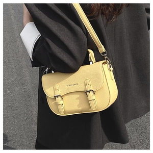 Close-up of yellow lychee pattern saddle bag styled with a dark suit on a model
