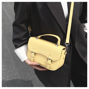 Detail of a bright yellow lychee leather saddle bag with silver buckles and handle