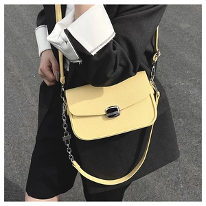 Detail of yellow pebbled leather saddle bag with silver metal clasp and chain strap