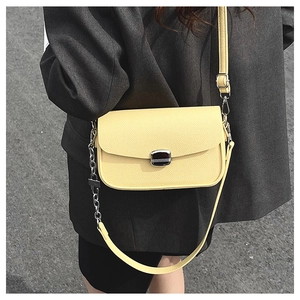 Detail of yellow saddle bag featuring pebble leather texture and silver chain strap