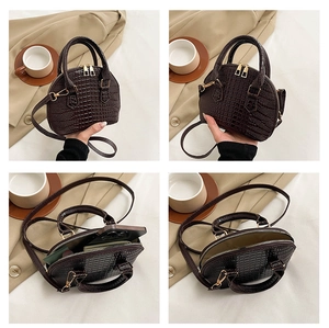 Detail view of brown crocodile texture shell bag showing interior storage and gold hardware