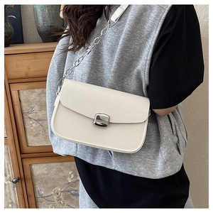 Detail of white lychee leather saddle bag with silver metal buckle and chain strap