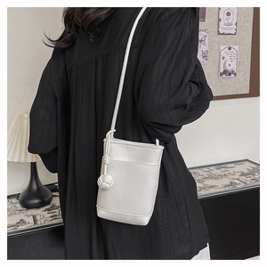 Gros plan d'un mini sac blanc avec bandoulière à nœuds porté par un mannequin
