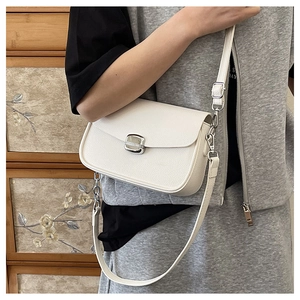 Detail of white pebbled leather saddle bag with silver buckle worn by a model