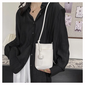 Détail du mini sac bandoulière blanc en cuir grainé avec pompon tressé élégant