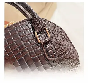 Close-up of deep brown crocodile embossed leather texture with gold metal hardware
