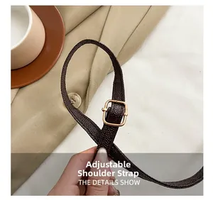 Detail of adjustable litchi texture leather shoulder strap with gold metal buckle